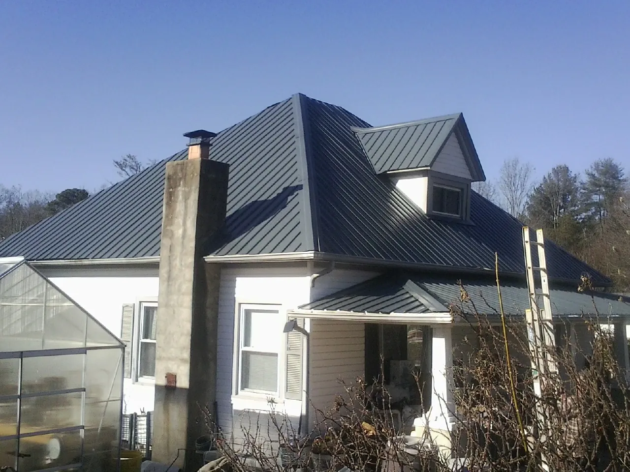 Dark blue standing seam metal roof on a white farmhouse with dormer — Slate & Tile Roof Repair by Roofing Brothers in Maryland Heights