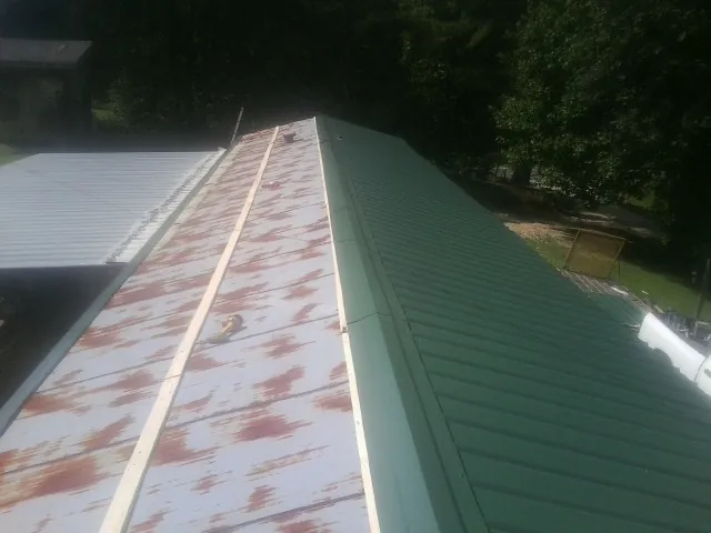 Old rusted panels beside newly installed green metal roofing — Wind Damage Roof Repair by Roofing Brothers in Maryland Heights