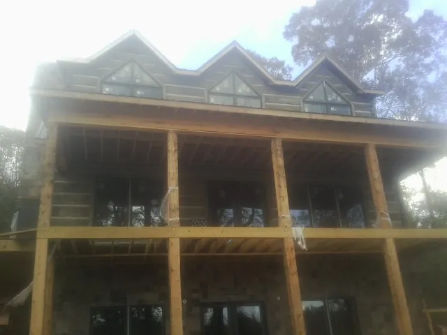 Dormers and porch framing on a large log home under construction — Roof Coating work by our crew in Maryland Heights