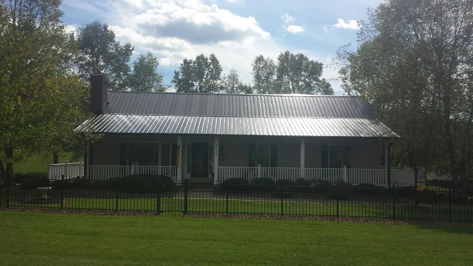 Gray metal roof on a brick ranch with a full width front porch — Gutter Guard Installation work by our crew in Maryland Heights