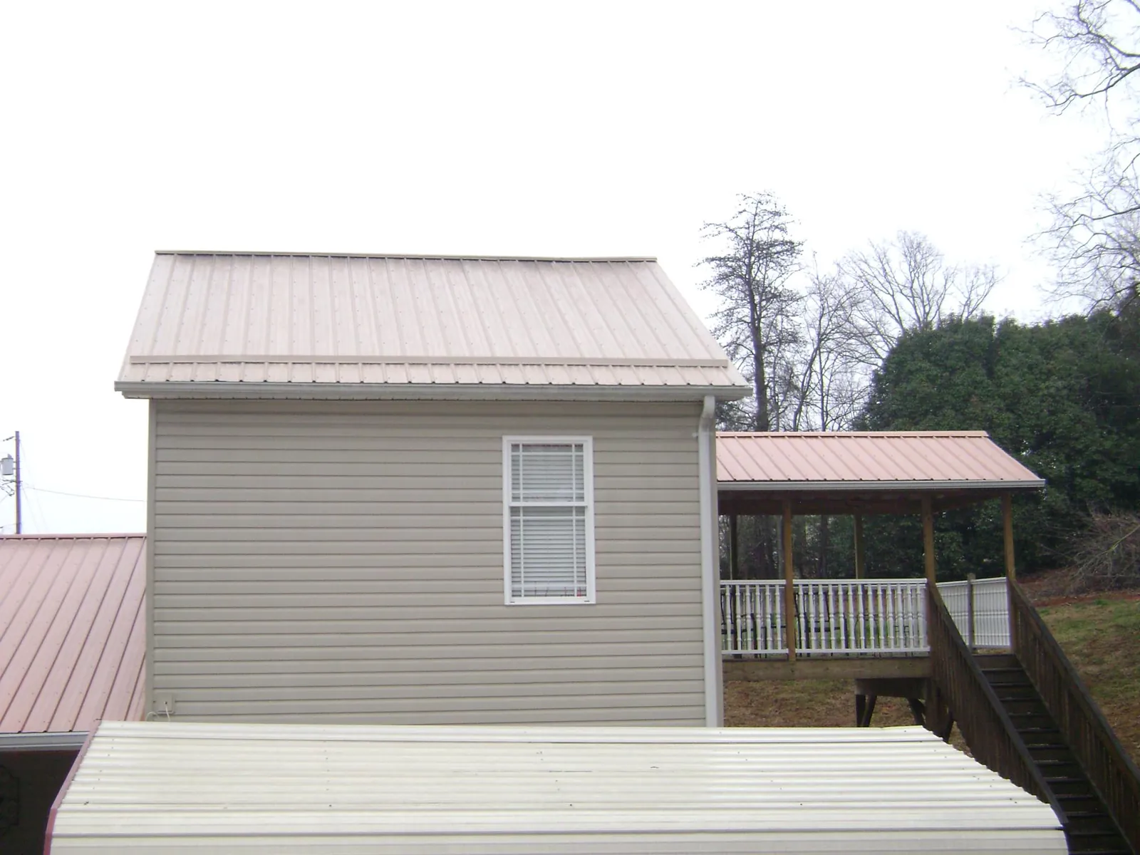 Tan metal roofs on a two story addition and attached porch, from a Roof Replacement job in Maryland Heights