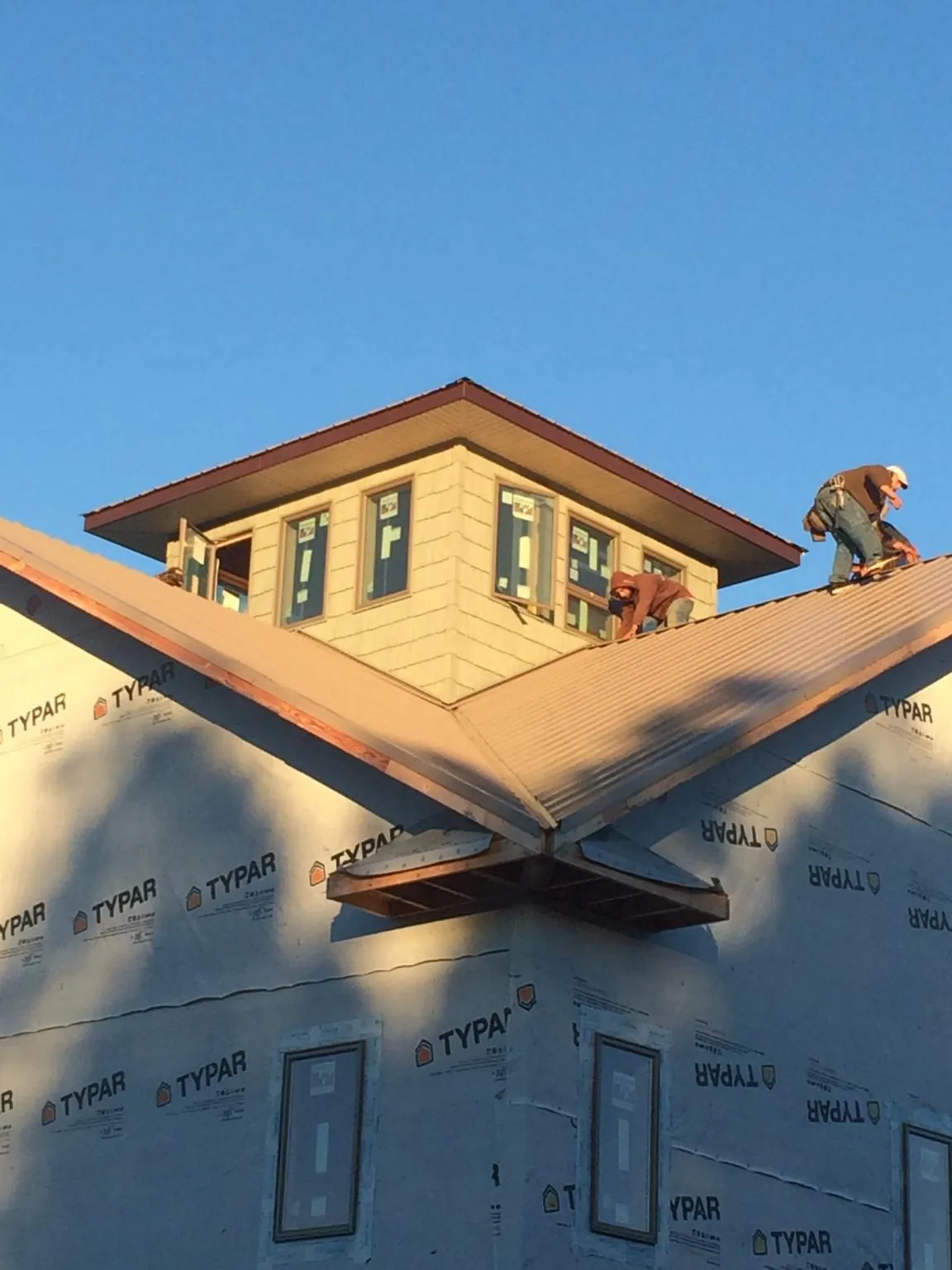 Roofers working around a rooftop cupola on a new metal roof at sunset — Roof Waterproofing in Maryland Heights by Roofing Brothers